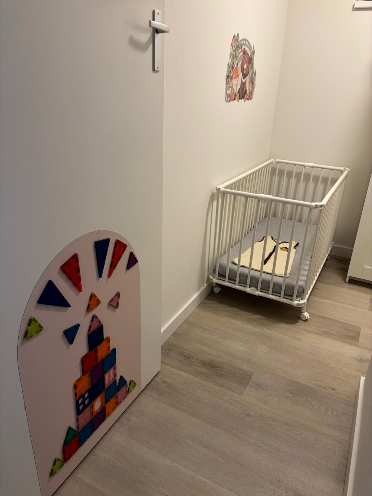 Rustige babykamer met wit bedje en speelmuur bij Gastouderopvang Liselotje